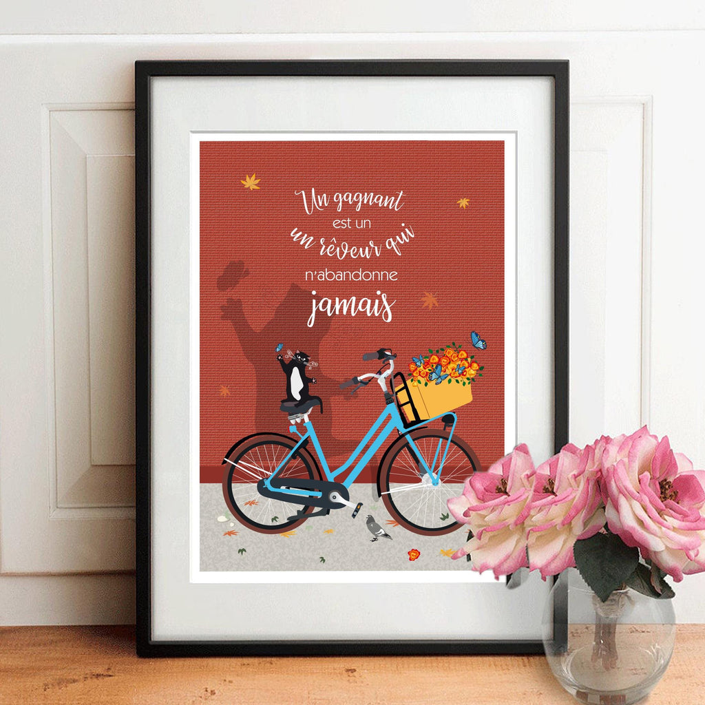 Affiche encadrée avec chat sur vélo bleu, fond rouge et citation décorative.
