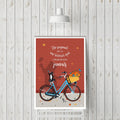 Affiche avec chat sur vélo bleu, fleurs colorées et texte décoratif sur fond rouge.