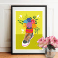 Affiche encadrée : basket fleurie multicolore sur fond jaune, cadre noir.